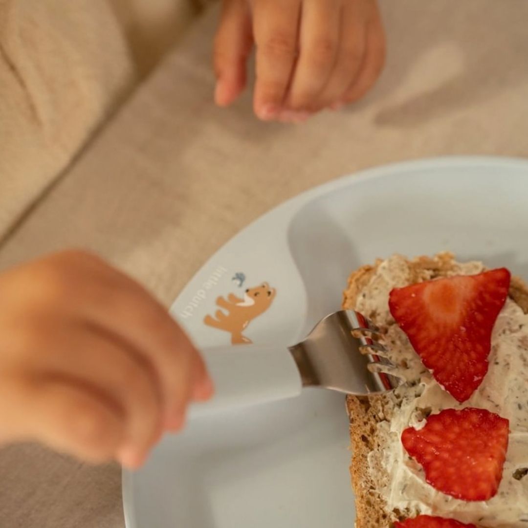Hånd holder på gaffel fra blå bestiksæt rustfrit stål med godt greb fra Mepal x Little Dutch 