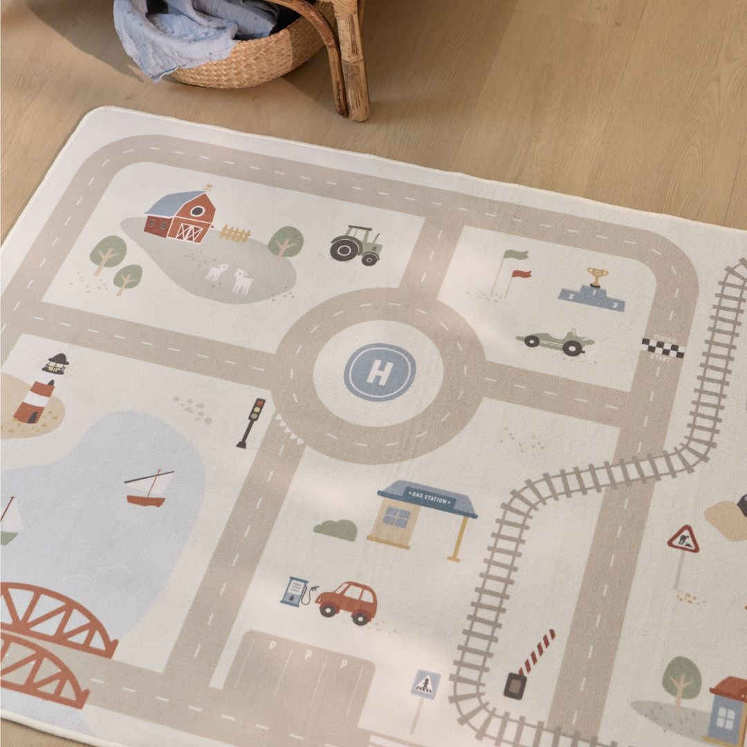 Bilbanemåtte med motiver af veje, togskinner, bondegård, helikopterlandingsplads og mere. Set oppefra på trægulv. Perfekt legemåtte til leg på gulvet til dit barn fra Little Dutch.