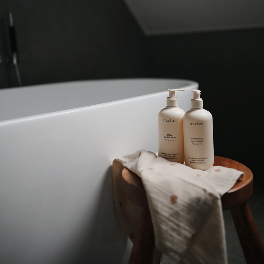 Mushie bodylotion til baby, 400 mL parfumefri, Svanemærket, produceret i Danmark. Her set på badeværelse sammen med Baby Shampoo i samme serie.

