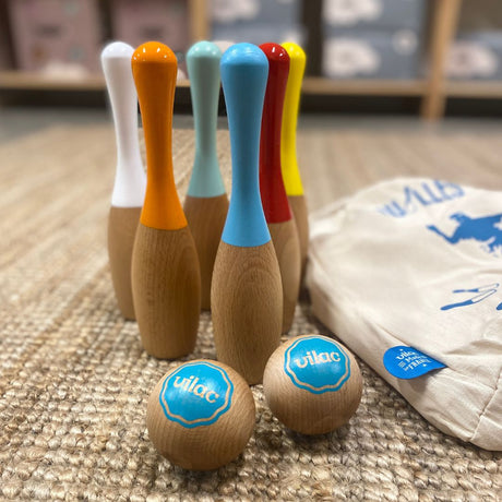 Bowlingsæt i træ i flotte farver med to kugler i træ, ligger på tæppe med stofpose ved siden af. Til børn fra 5 år.