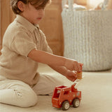 Brandbil med træfigur: en dreng leger med en rød træbrandbil og bruger stigen til redning.