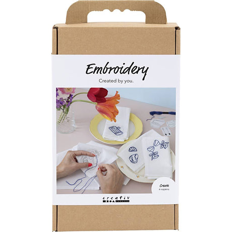 brun papæske med billede af servietter med blåt broderi, lavet med diy broderisæt til kreativ fordybelse.