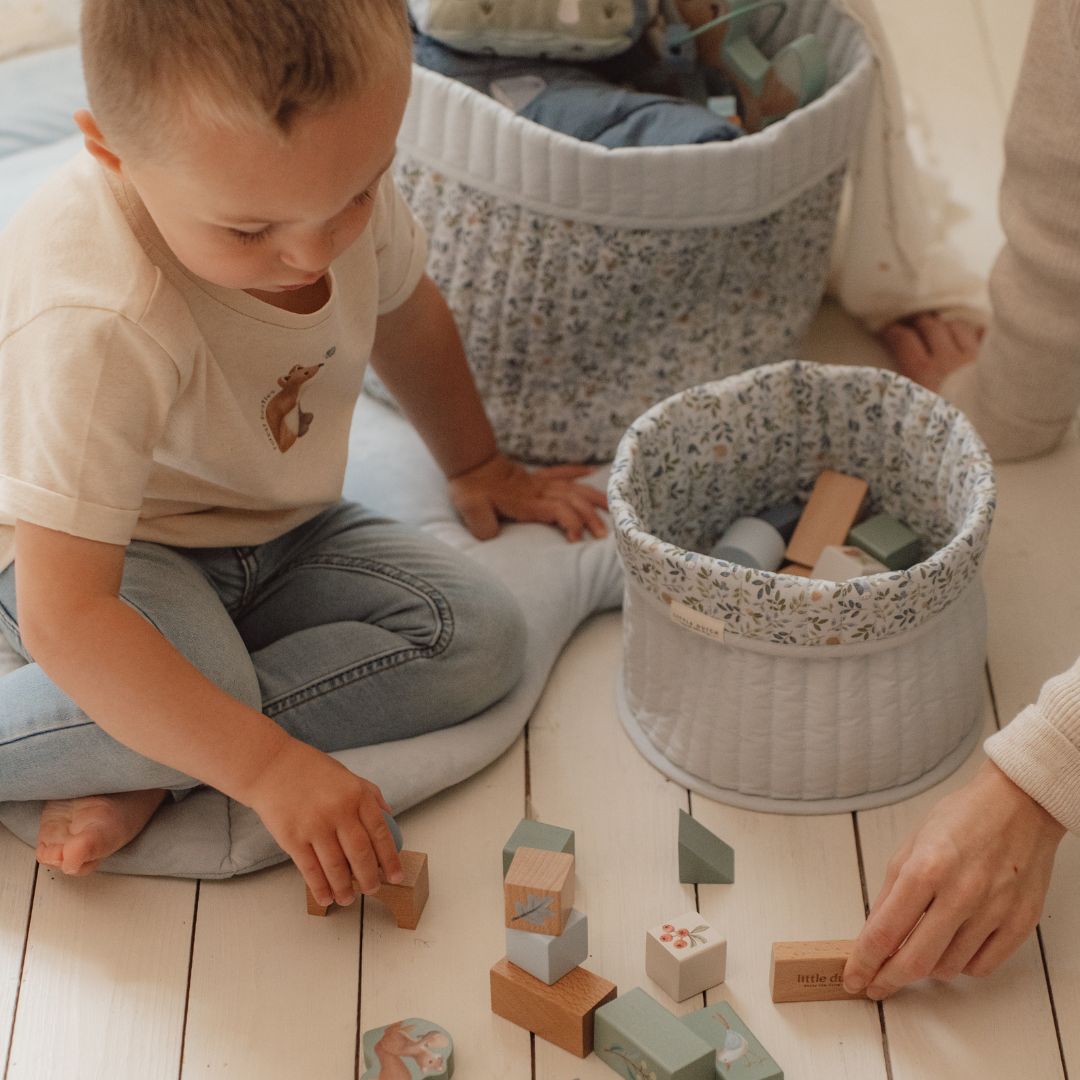 Barn leger med Byggeklodser i træ i forskellige farver, fra Little Dutch, i hyggelig stue.