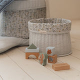 Træklodser i blå nuancer ved siden af en flettet opbevaringskurv, perfekt til leg.