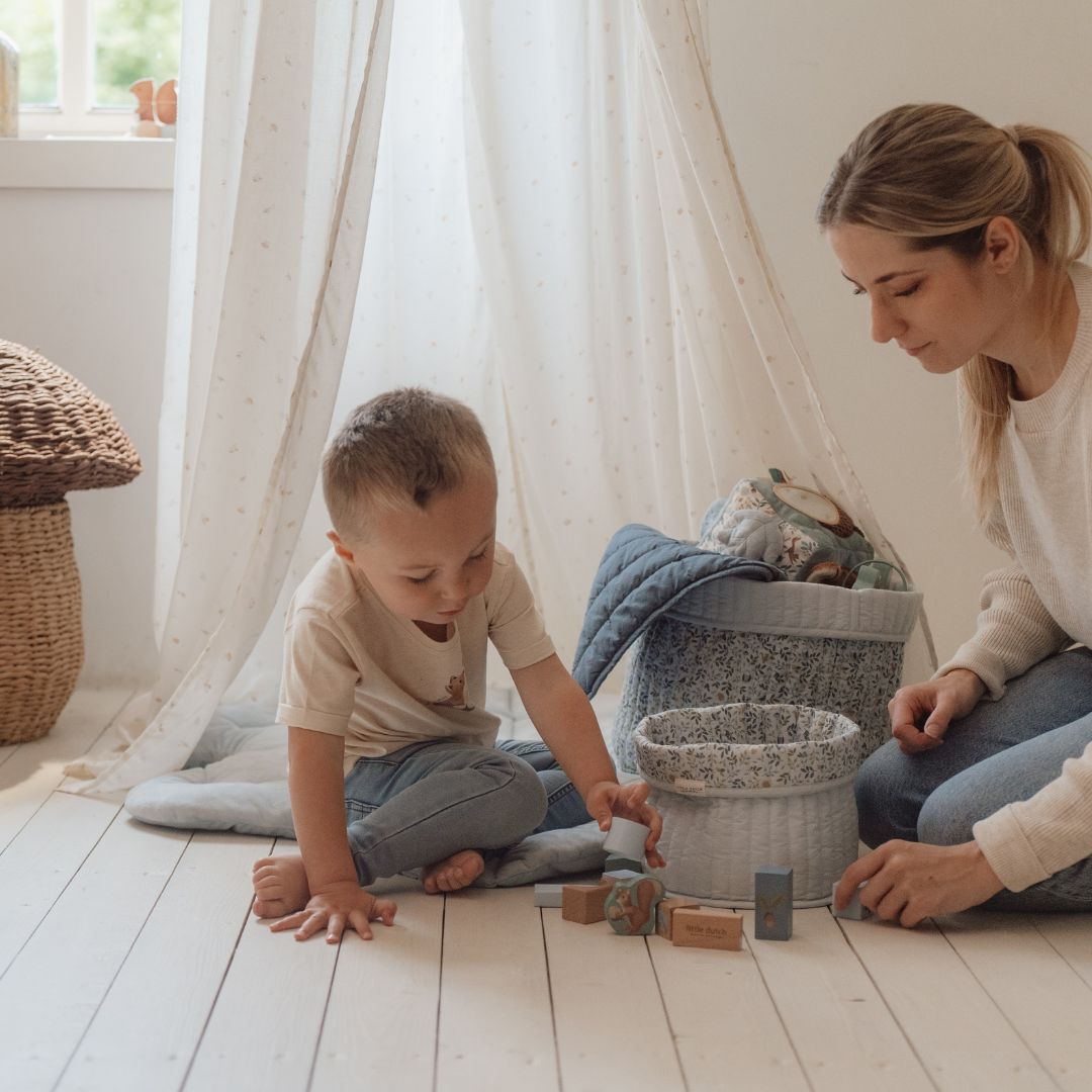 Mor og barn leger med Byggeklodser i træ i et lyst og hyggeligt rum.
