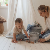 Mor og barn leger med Byggeklodser i træ i et lyst og hyggeligt rum.