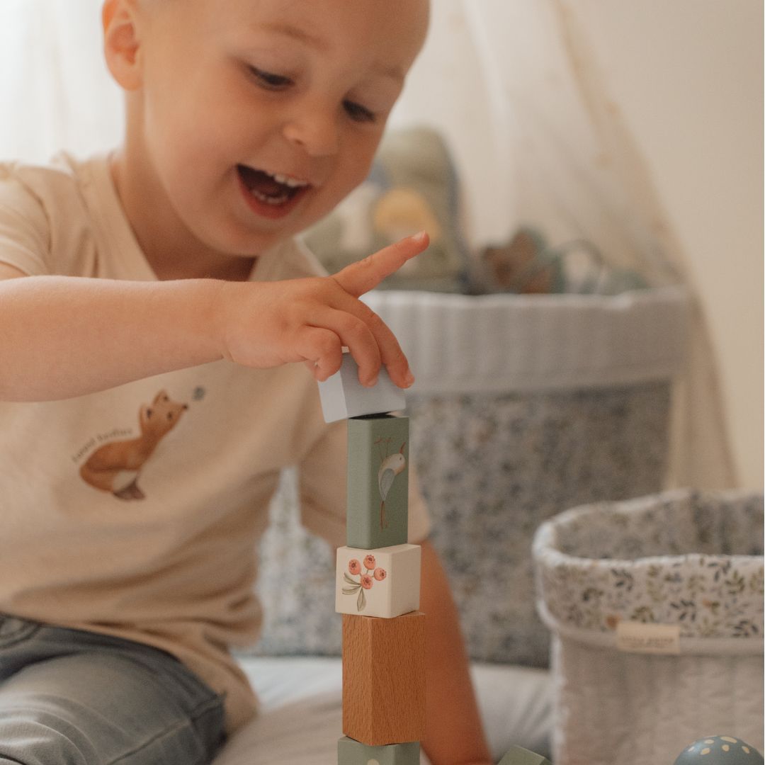 Glad dreng bygger med blå træklodser fra Little Dutch, inspireret af skovens dyr.