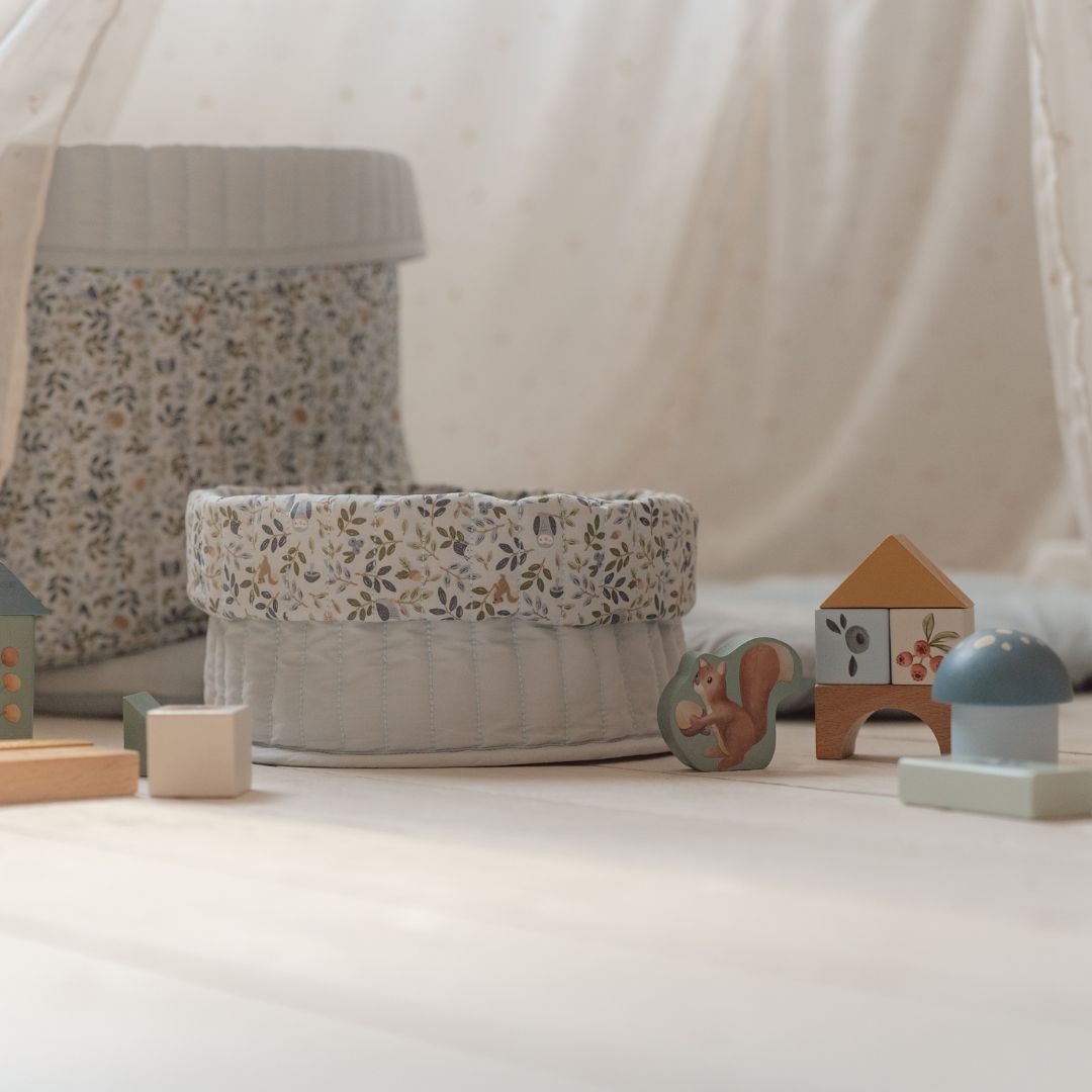 Farverige byggeklodser og opbevaringskurve i lyse, bløde farver set i stue.