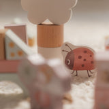 Farverige træklodser med motiver af feer og dyr, inklusive en mariehøne, set tæt på