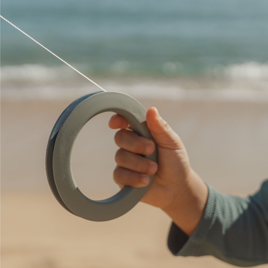 hånd holder håndtag til blå drage med motiver fra havet