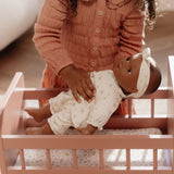 Dukke Noa med udstyr, 36 cm. Barn leger med Dukke Noa i en pink vugge, iført blødt tøj med blomster.