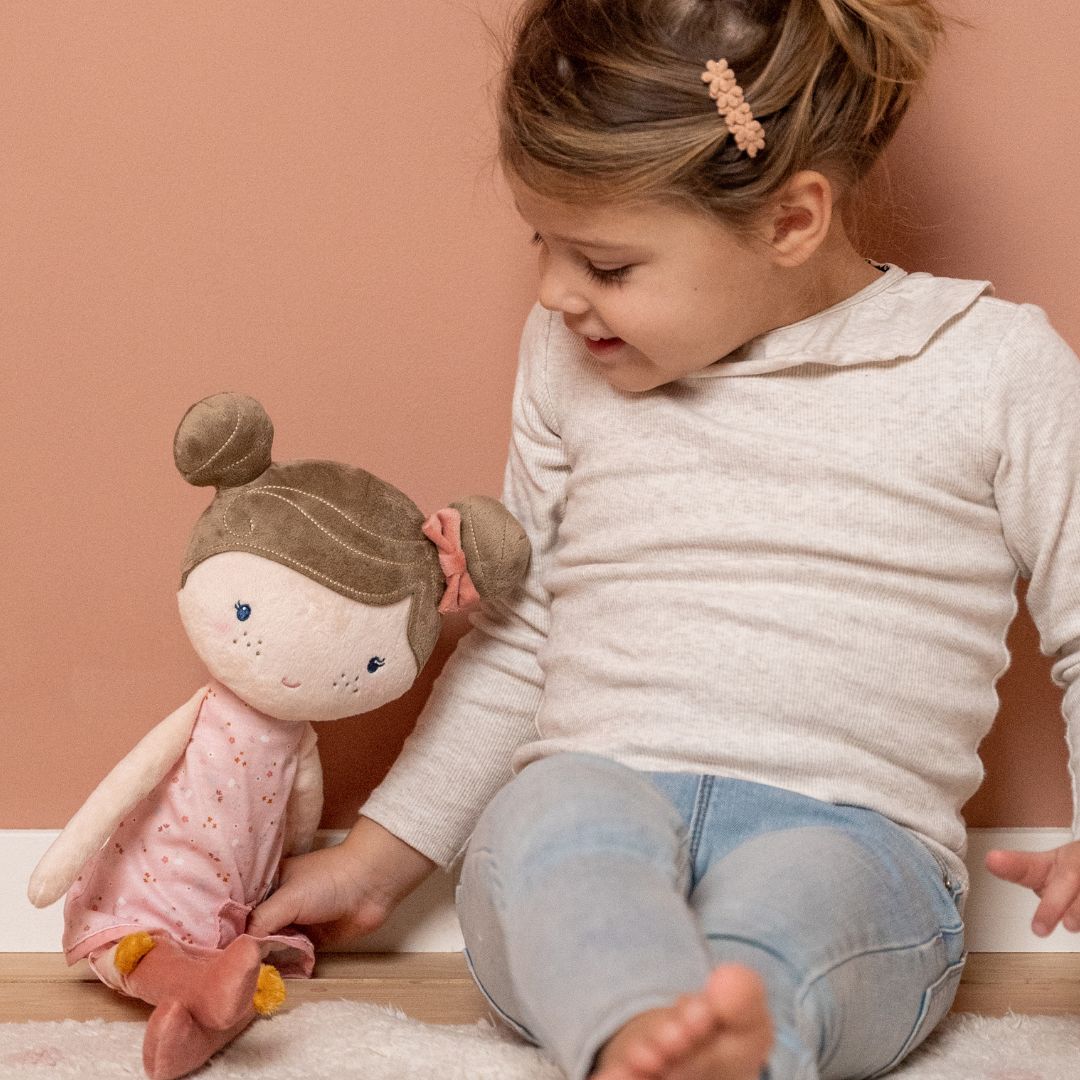 Dukke, Rosa 50 cm med barn, der leger, og smiler, både dukke og barn sidder op ad rosa væg.