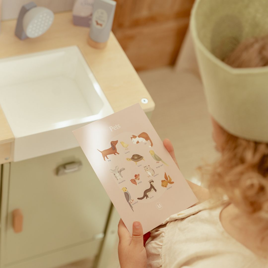 Barn leger med dyrlægeklinik fra Little Dutch og viser kort i træ med søde kæledyr.