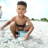 dreng leger på strand med 4 små blå sandforme i silikone, perfekt til små hænder fra 1 år og op, høj kvalitet fra Scrunch