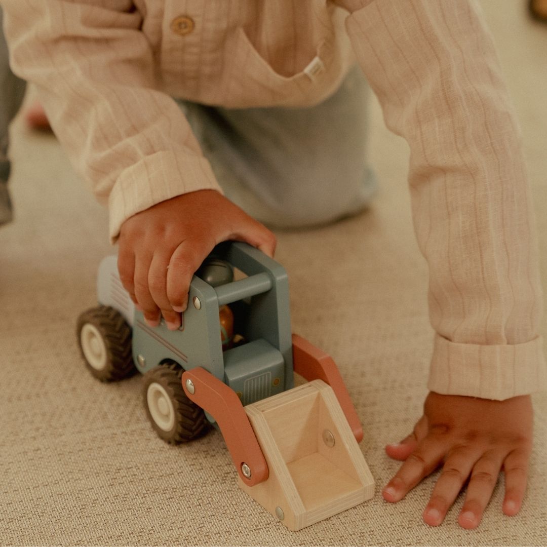 Barn leger med en blå frontlæsser, i træ med træfigur, der har en stor skovl til sjov på byggepladsen