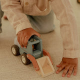 Barn leger med en blå frontlæsser, i træ med træfigur, der har en stor skovl til sjov på byggepladsen