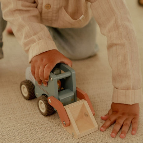 Barn leger med en blå frontlæsser, i træ med træfigur, der har en stor skovl til sjov på byggepladsen