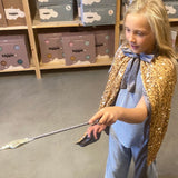pige i lang guldkappe med pailletter kaster en trylleformular med tryllestav i guld . begge dele fra Mimi & Lula fås hos Nordic Simply