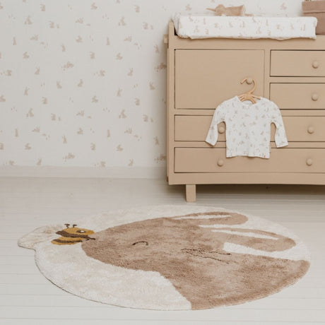 Gulvtæppe med kanin, rundt beige legetæppe i økologisk bomuld med sød kanin og bi, set i børneværelse.
