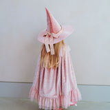 Pige set bagfra med lang rosa velourkappe og høj rosa hat i velour med guldstjerner og bredt guld bindebånd, magisk fehat, prinsessehat eller heksehat til barn 3-8 år