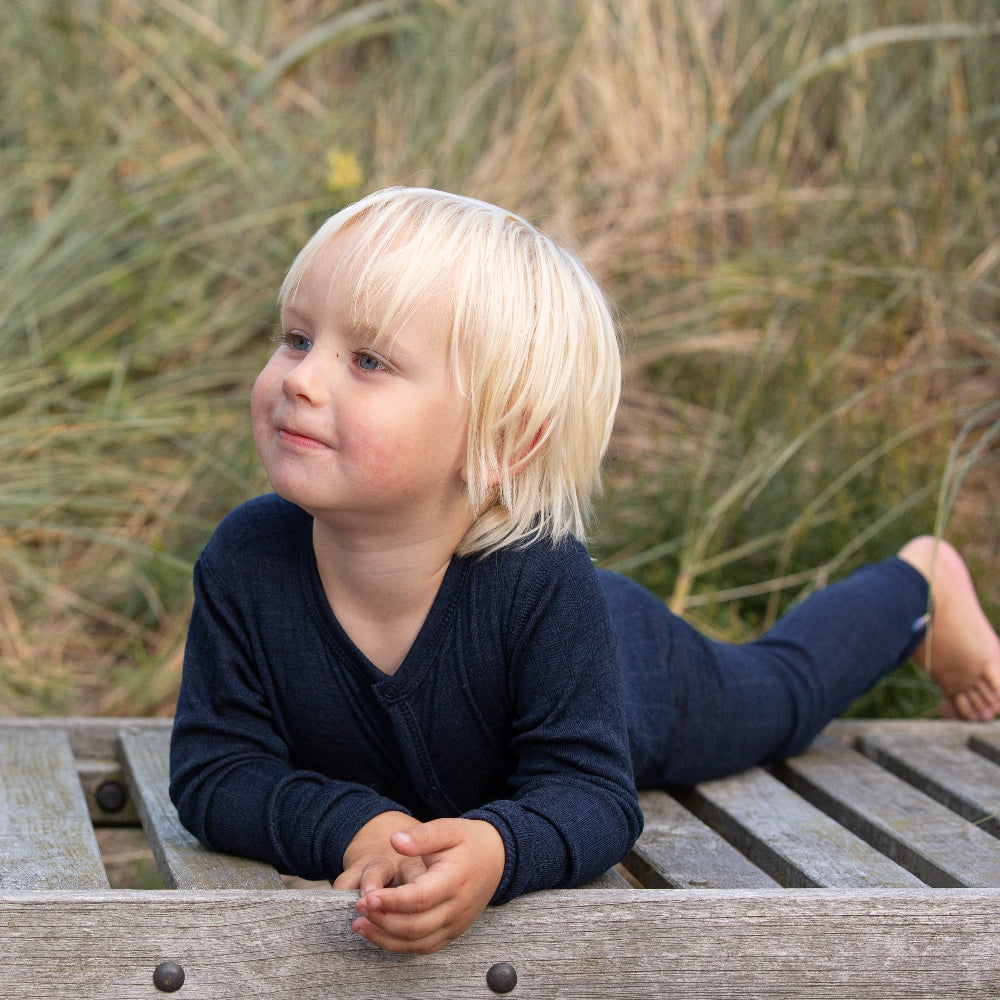 barn udendørs i mørkeblå heldragt med lange ærmer. Joha jumpsuit i uld/silke med tynd stribe i stoffet og knapper foran. Farve navy.