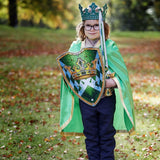 Barn med grøn kappe til konge, skjold, sværd og krone. Flot skinnende grøn kongekappe til barn, fås hos Nordic Simply