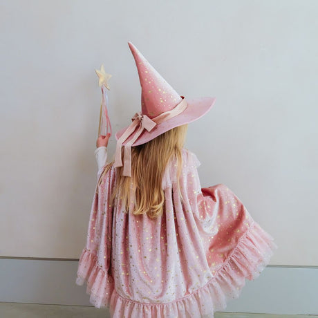 Pige set bagfra med høj rosa hat, tryllestav og lang rosa kappe i fed velour med guldstjerner. Magisk kappe til barn 3-8 år i høj kvalitet fra Mimi & Lula. 