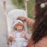 pige sidder ved rosa klapvogn med dukke i