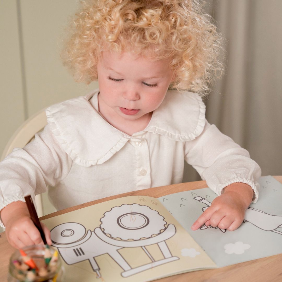 Barn tegner i malebog med motiver af bondegården fra Little Dutch. God fra 2 år og op
