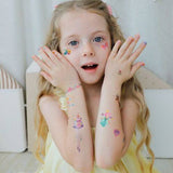 Glowing girl showing off colorful flower stickers on hands and arms, enjoying creativity with fun tattoos.