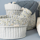 2 runde opbevaringskurve i lyseblå med blomstret ombukket kant, 1 stor kurv og 1 lille kurv med stofbleer ved pusleplads. Kurvene er quiltet  i 100% økologisk bomuld og kan vendes. Fra Little Dutch Forest Adventure kollektion.