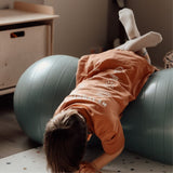 Barn tumler på blå peanutformet balancebold til sanseleg, motorisk udvikling og balance fra Find that Hippo.