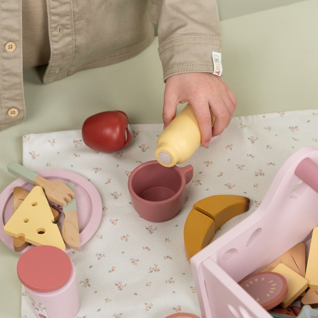 Barn leger med rosa picnicsæt i træ til rolle-og fantasileg. Indeholder picnictæppe, kopper, tallerkener, bestik, brød, kager, frugt og andre gode sager. Legesæt fra Little Dutch i høj kvalitet.