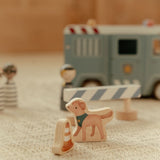 Politibil med træfigurer og hund, står i opsætning på lyst gulvtæppe med politibetjente og en vejspærring.