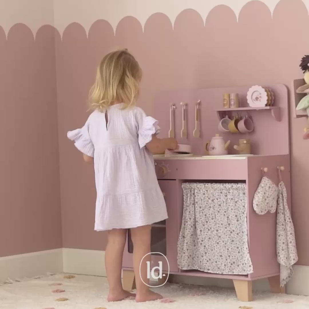 lille pige leger i rosa legekøkken i træ, her tilbereder hun mad på komfuret, kager i ovnen og te på tekanden, find det smukke pink køkken til børn hos Nordic Simply