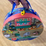 Hånd holder puslespil med junglens dyr og Noahs Ark, 100 brikker, i rund æske med håndtag. Godt til 5 år +