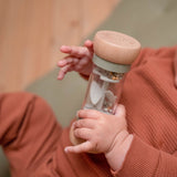 Regnmager grøn sanselegetøj, baby holder en farverig regnmager med perler, der simulerer regnlyde.