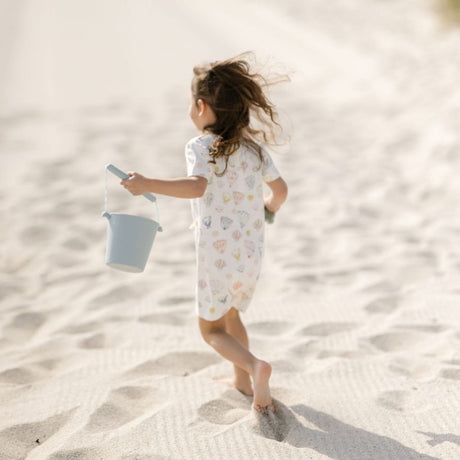 Barn leger på strand med blå spand i silikone, kan foldes, god til ferie og rejser