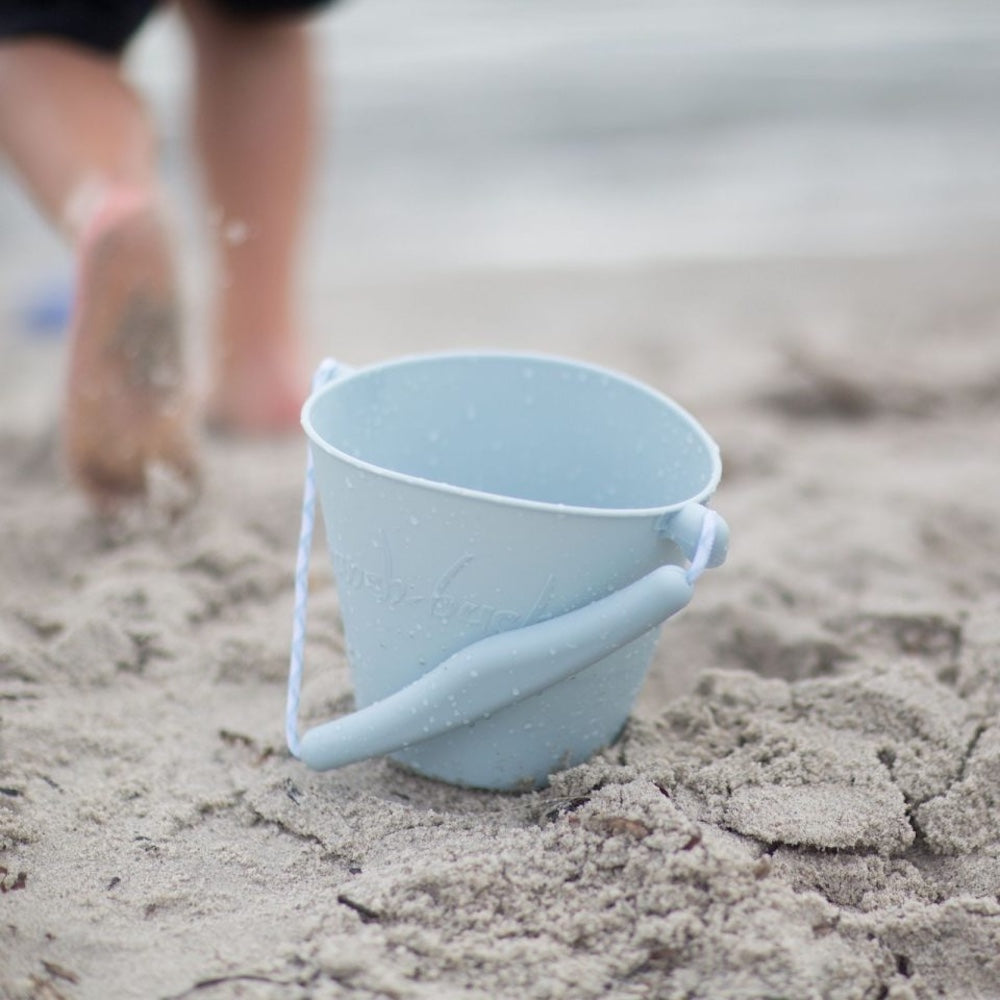blå spand i silikone, set i sand på strand, god til ferie og rejser