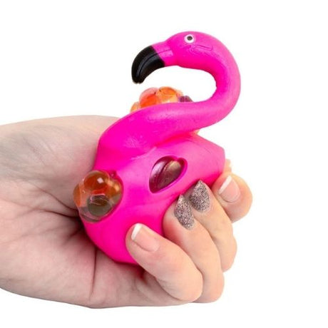 Hånd holder en sjov pink squeeze flamingo med farverige hjerter til stressaflastning og leg.