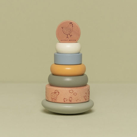 Stabeltårn med 6 stabelringe i lys blå, grøn beige farver med bondegårdstema set på grøn baggrund. Stabletårn i træ fra Little Dutch godt til hånd-øje koordination og finmotorik fra 12 måneder og op, fås hos Nordic Simply.