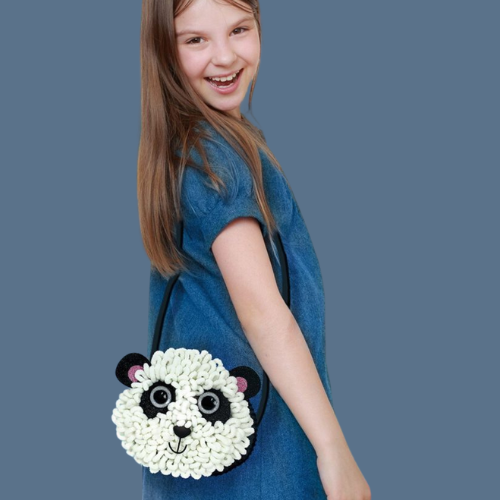 Pige med DIY skuldertaske med panda i plys, hun selv har lavet. Kreativt sæt til børn fra 6 år og op fra Avenir, fås hos Nordic Simply