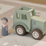 Grøn traktor i træ med træfigur foran, set på matchende bilbanemåtte. Perfekt legetøj til tumling fra 18 måmeder og op.
