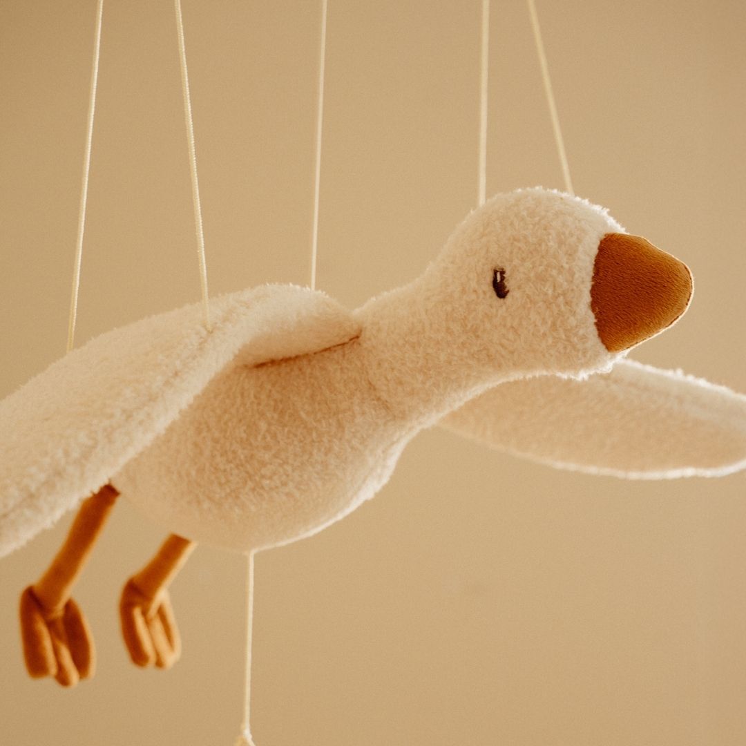 Uro med flyvende hvid gås der svæver gennem luften i et børneværelse, tilføjer ro og eventyr.