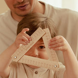 Værktøjskasse 18 dele – Barn holder en trekantet lineal i træ med en voksen i baggrunden.